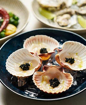 a plate of seafood in served in seashells on a table