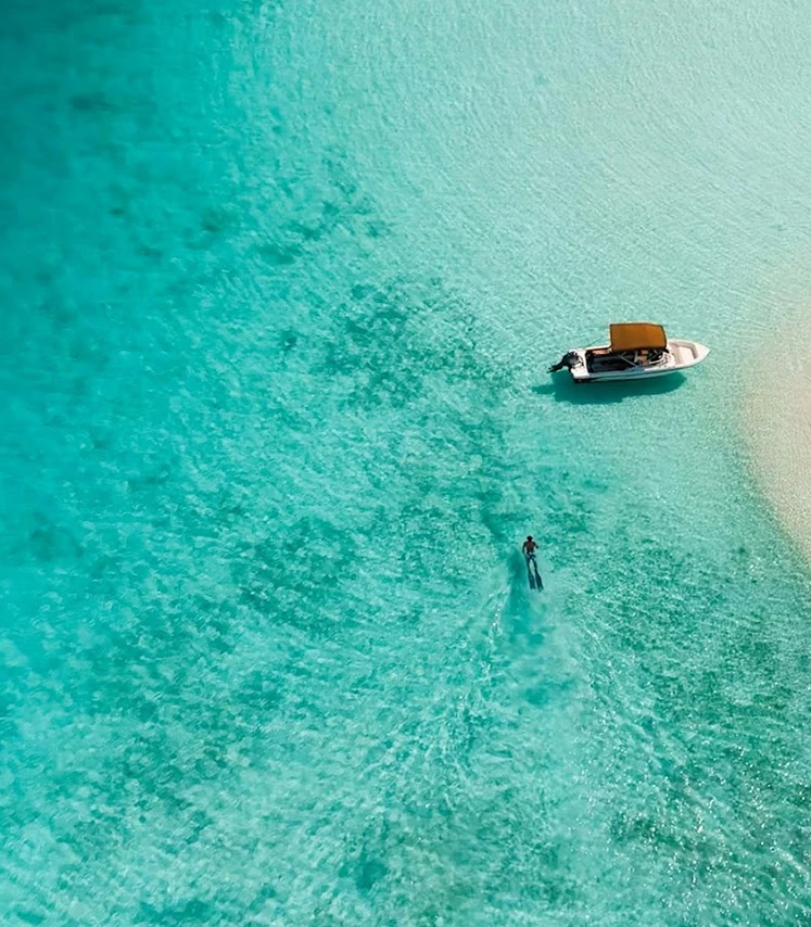 a person swimming near a boat in clear turquoise water