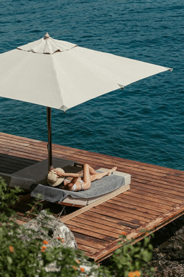 a woman lying on a lounge chair under an umbrella