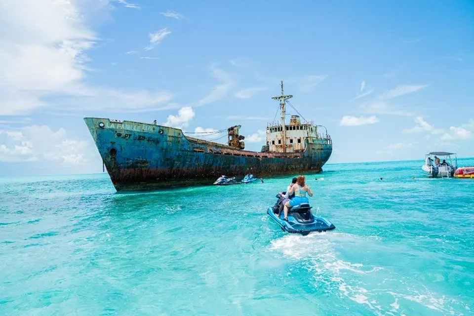 people on a jet ski in the water near a large ship