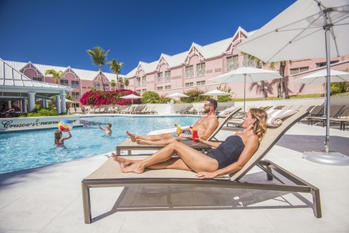 a man and woman sitting on lounge chairs by a pool