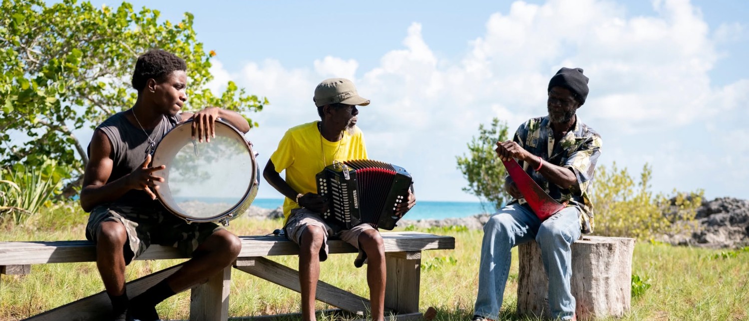 a group of men sitting on a bench playing instruments