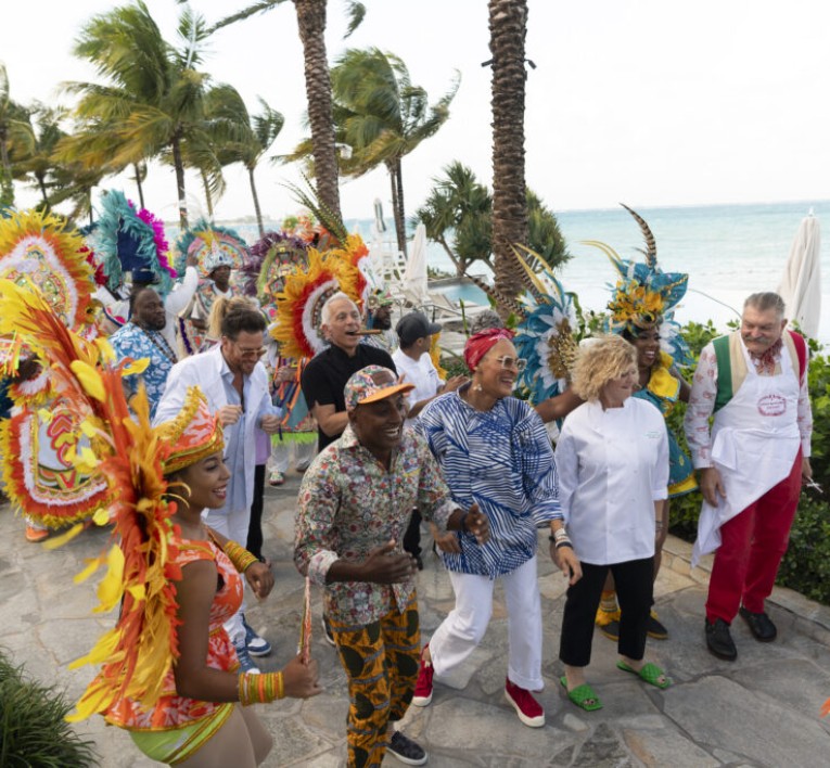 a group of people walking on a path with palm trees and a body of water