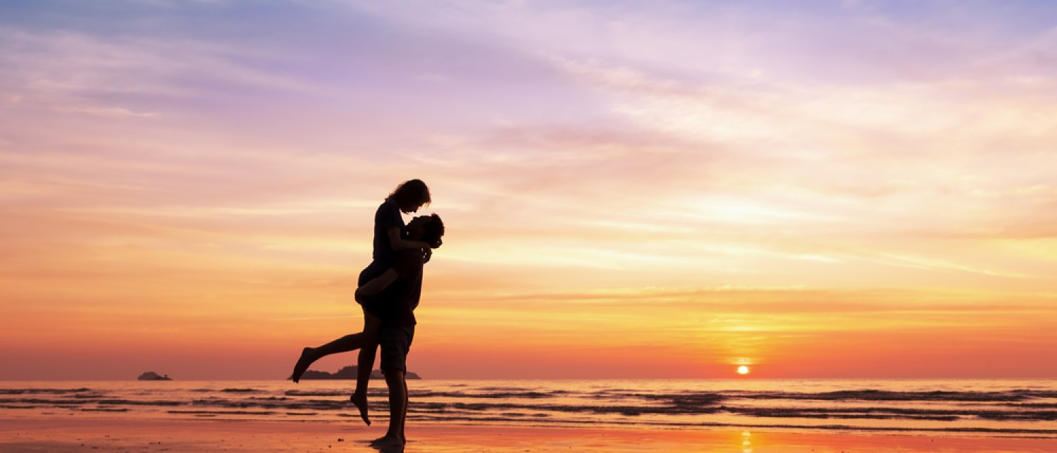 a man carrying a woman on his back on a beach