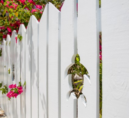 a white picket fence with a hole in it