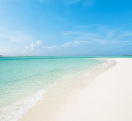 a white sand beach with blue water and blue sky