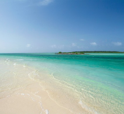 a beach with clear blue water and a small island