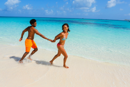 a man and woman holding hands on a beach