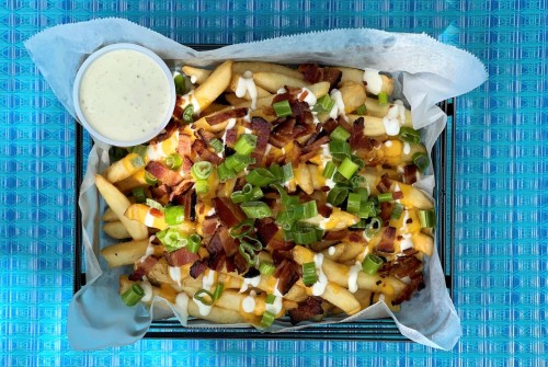 a plate of french fries with bacon and green onions