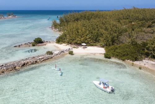 a group of people on a boat in the water with Crane Beach in the background