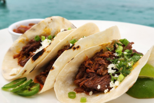 a plate of tacos with a marinade in the background