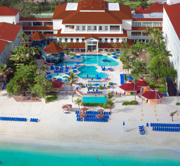 a resort with a pool and chairs on the beach
