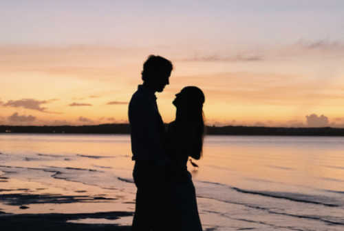 a silhouette of a man and woman kissing on a beach
