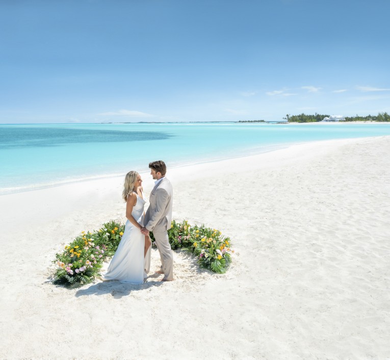 a man and woman holding hands on a beach