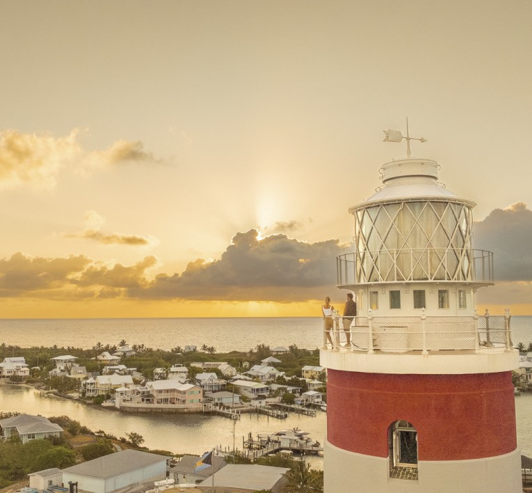 a lighthouse with a body of water and a sunset
