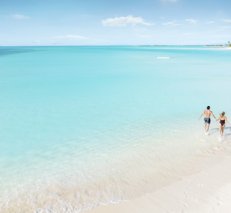 a couple of people running on a beach