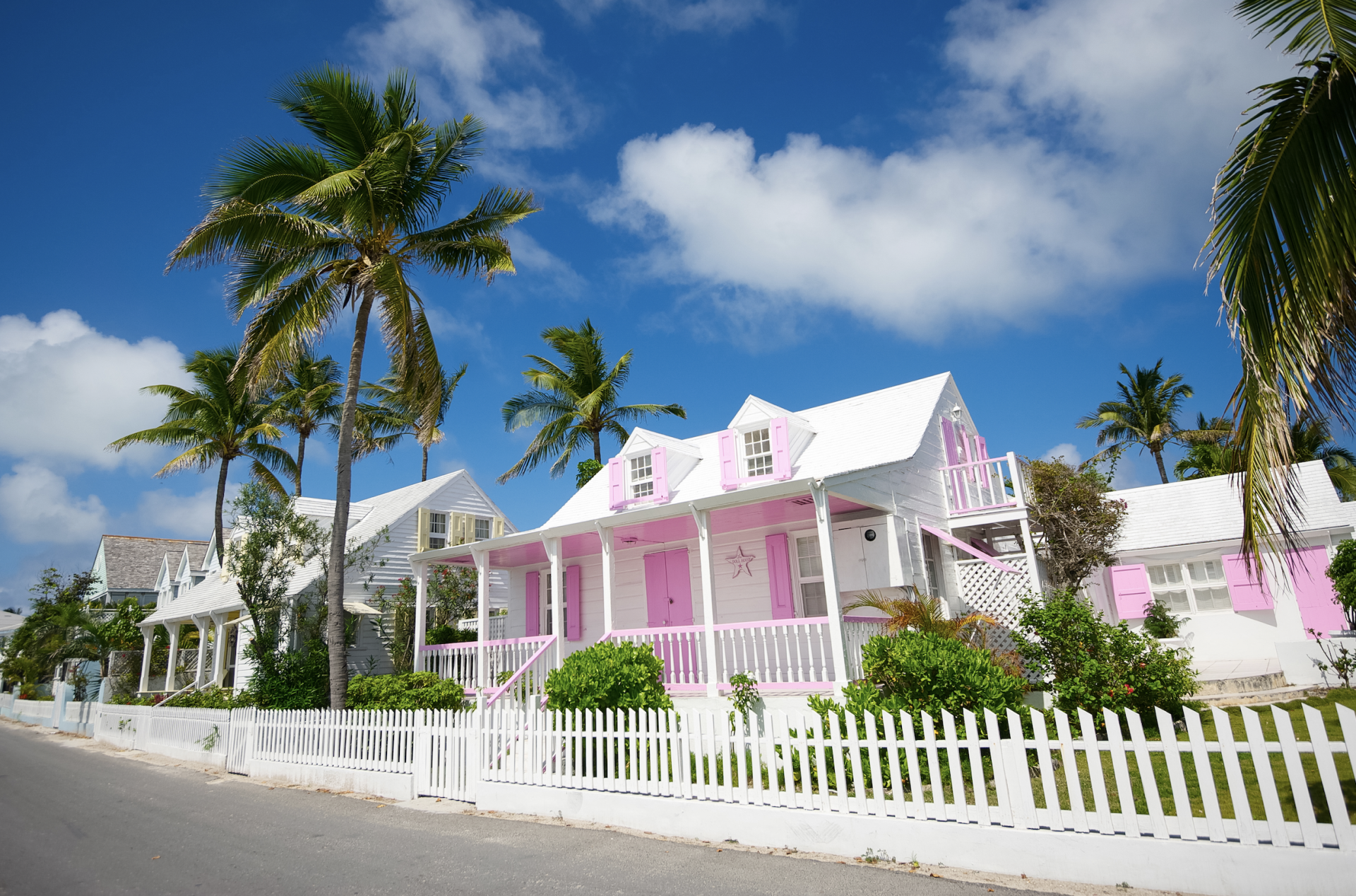 a house with palm trees and a white fence