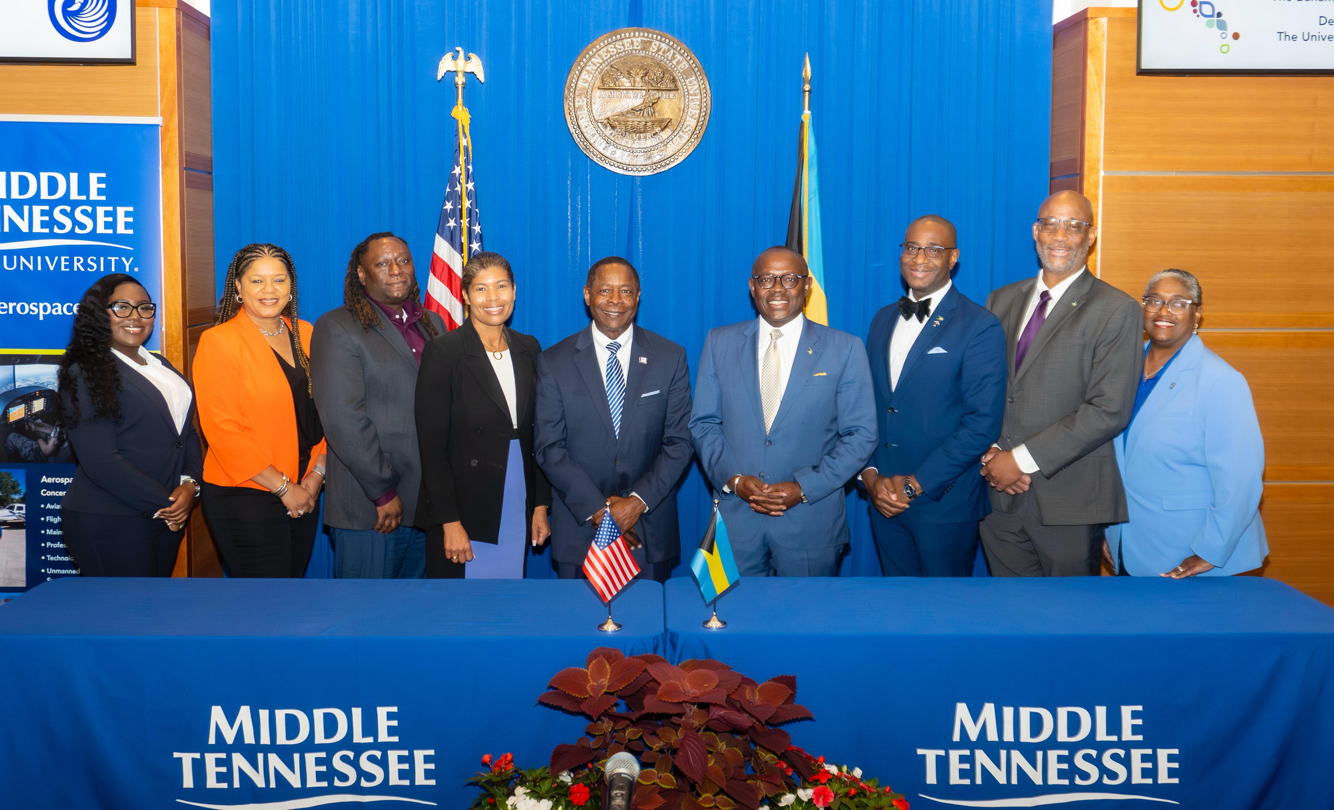 a group of people standing in front of a blue table with flags