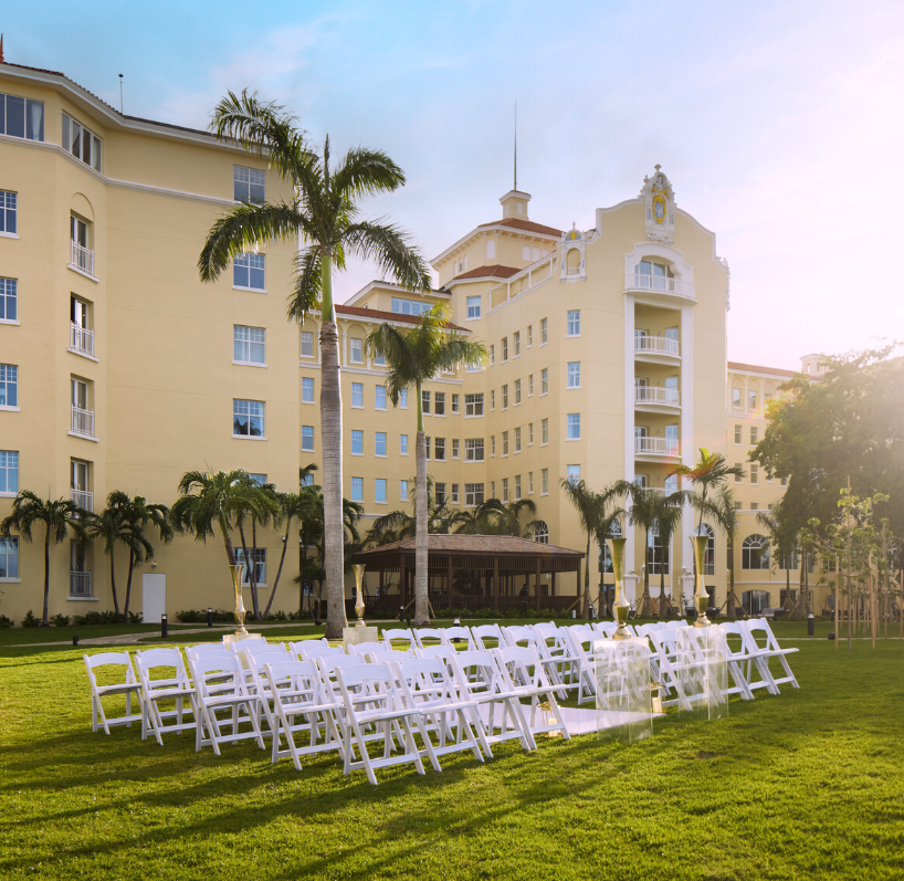 a group of white chairs in a grassy area with a large building in the background