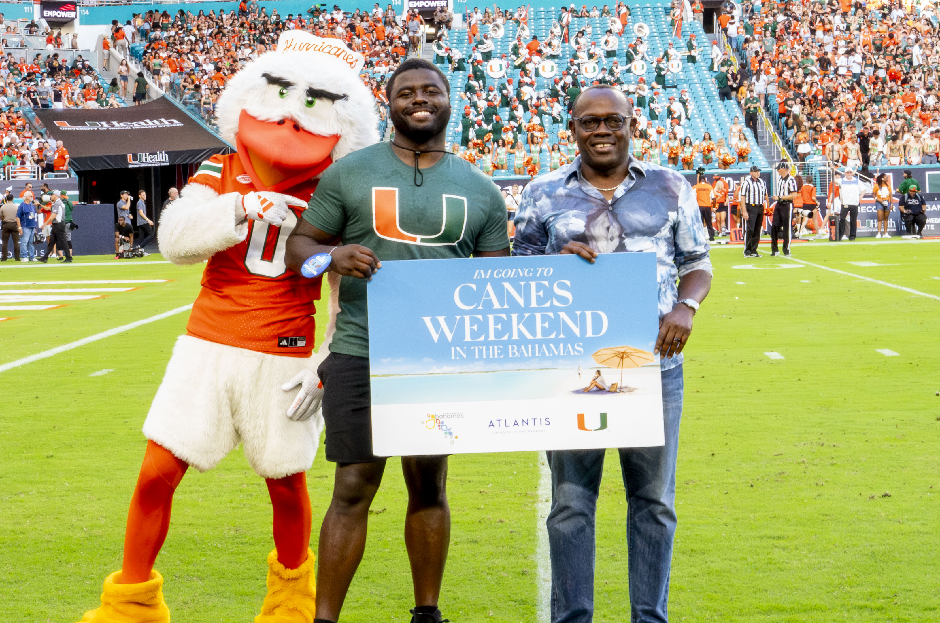two men standing on a football field holding a sign